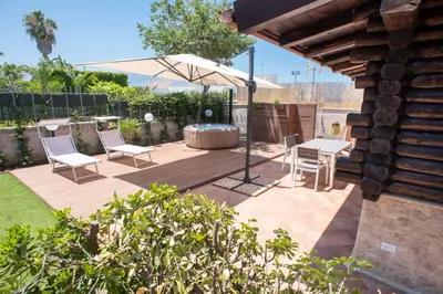 a patio with a table and chairs and an umbrella at Chalet Seaview by AR Group Hotels in Isola delle Femmine