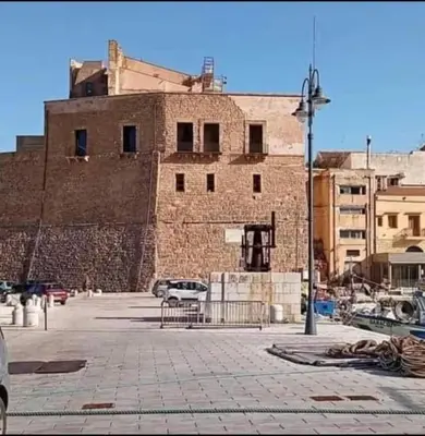a large brick building with cars parked in a parking lot at Casa Fugardi in Castellammare del Golfo