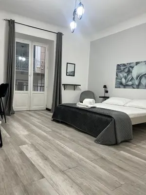 a bedroom with a large bed and a wooden floor at BIBI rooms and suite in Palermo