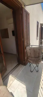 a chair sitting in a living room with an open door at Appartamento Arancio in San Vito lo Capo