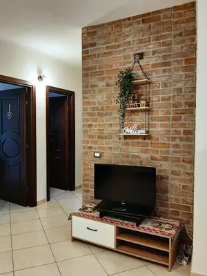 a living room with a tv on a brick wall at Stella del Centro Apartment in Palermo