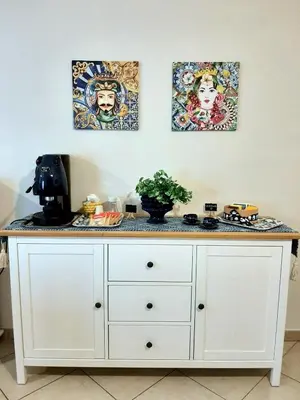 a white counter with three paintings on the wall at Stella del Centro Apartment in Palermo