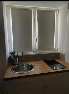 a kitchen counter with a sink and two windows at Calvello studio apartment in Palermo