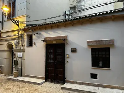 a white building with a black door on a street at Carmine House in Monreale