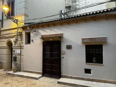 a white building with a black door on a street at Carmine House in Monreale