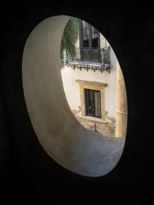 a view of a building through a round window at Palazzo Santa Ninfa - Luxury Mansion in Palermo