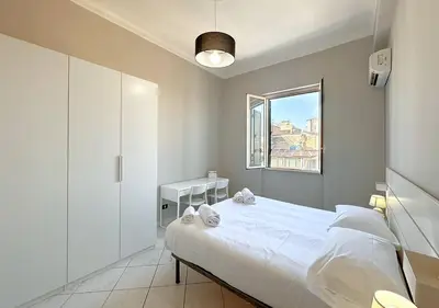 a white bedroom with a bed and a window at Solemar Sicilia - Casa Scordia in Palermo