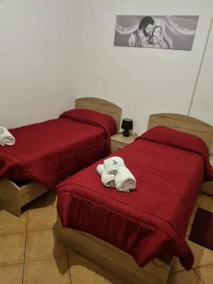 two beds in a room with red sheets and towels at Le stanze di Aurora in Palermo