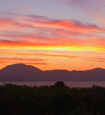 a sunset over the water with mountains in the background at Villetta indipendente a Balestrate in Balestrate