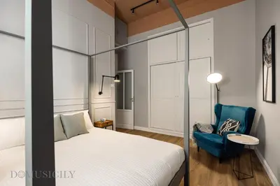 a bedroom with a bed and a blue chair at Constance Luxury Apartment by DomuSicily in Palermo