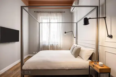 a bedroom with a canopy bed with a tv on the wall at Constance Luxury Apartment by DomuSicily in Palermo