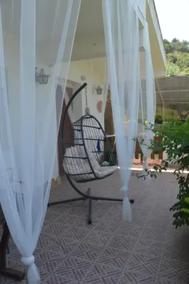 a swing on a porch with white curtains at Villino Anna e Pippino in Calatafimi