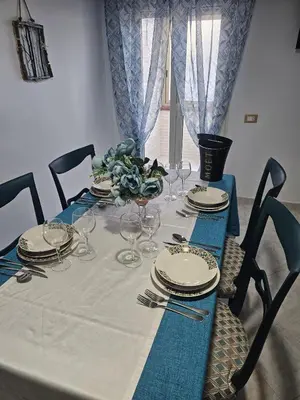 a dining table with a blue and white table cloth and chairs at A casa di Livia in Villabate