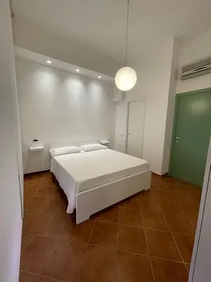 a bedroom with a white bed and a green door at Vittorosa House in Palermo