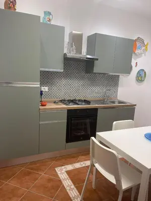 a kitchen with white cabinets and a table and a table and a refrigerator at Vittorosa House in Palermo
