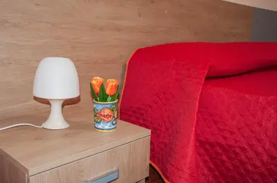a vase with orange flowers on a night stand next to a bed at Casa Vacanze Caruso in Carini