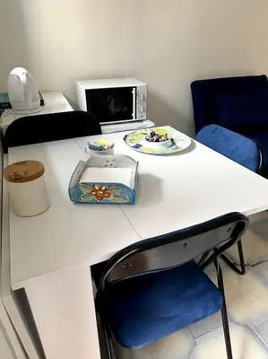 a white table with a microwave and blue chairs at Residenza Saturno 7 in Palermo
