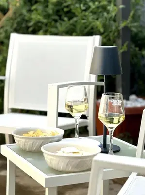 a table with two glasses of white wine and a lamp at Residenza Saturno 7 in Palermo