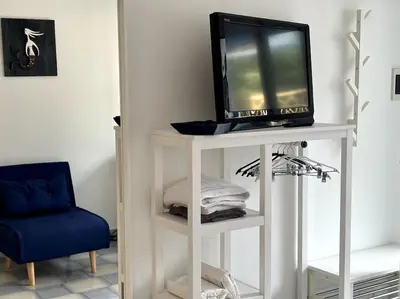 a tv on a white stand with a blue chair at Residenza Saturno 7 in Palermo