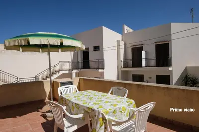 a table and chairs on a balcony with an umbrella at Appartamenti Esther in San Vito lo Capo