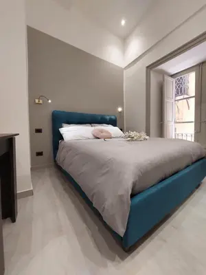 a bed with a blue head board in a bedroom at Il Mio Canto Home in Palermo