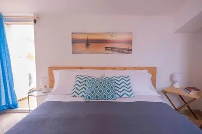 a bed with blue and white pillows in a bedroom at Cefalù, Lascari - Appartamento moderno vicino al mare in Lascari