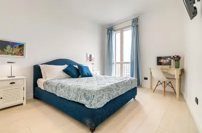 a bedroom with a blue bed and a desk at GuestHost - La Cala Sea View Apartment with Balconies in Palermo