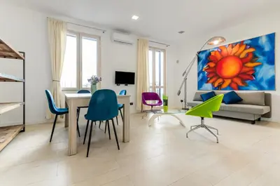 a living room with a table and chairs and a painting at GuestHost - La Cala Sea View Apartment with Balconies in Palermo