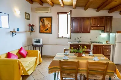 a living room with a table and a kitchen at Le Scalette in Castellammare del Golfo