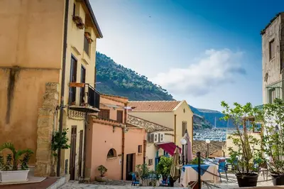 an alley with buildings and a view of a harbor at Le Scalette in Castellammare del Golfo