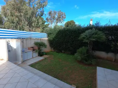 a backyard with a blue and white umbrella and a yard at Villa Ipomea in San Vito lo Capo