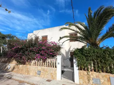 a white house with a fence and a palm tree at Villa Ipomea in San Vito lo Capo