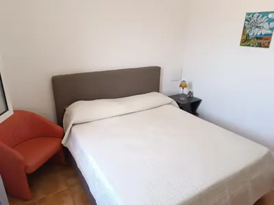 a small bedroom with a bed and a chair at Le Tremar Carini Poseidon in Carini