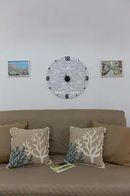 a clock on the wall above a couch at appartamento centro storico - La casuzza alla Cala in Palermo
