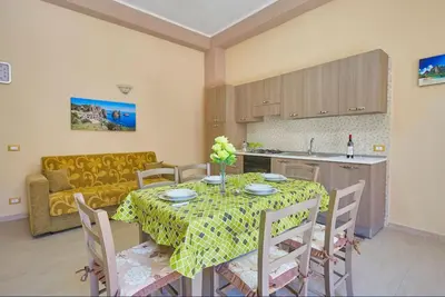 a kitchen and living room with a table and a couch at Casa Maria Stella Scopello in Scopello