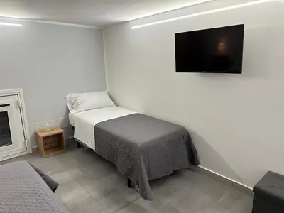a bedroom with a bed and a tv on the wall at Vespro House in Palermo