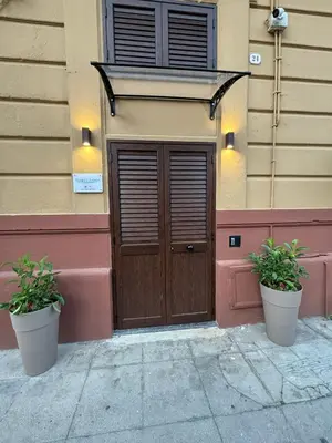a building with a wooden door and two potted plants at Vespro House in Palermo