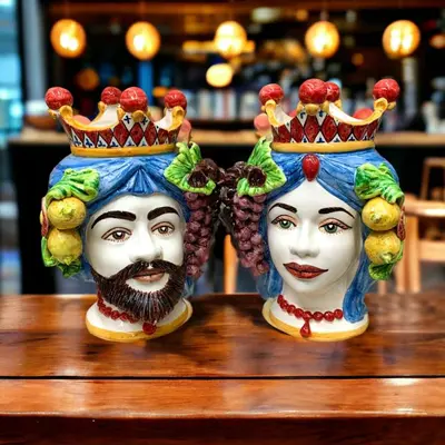 two masks with crowns on their heads on a table at Politeama my Suite in Palermo