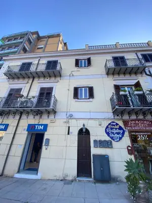 a tall white building with a door and windows at Il falchetto in Palermo