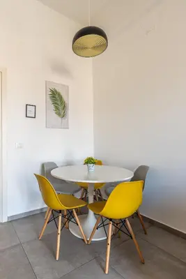 a dining room with a white table and yellow chairs at Lumar Sicilia - Magione in Palermo