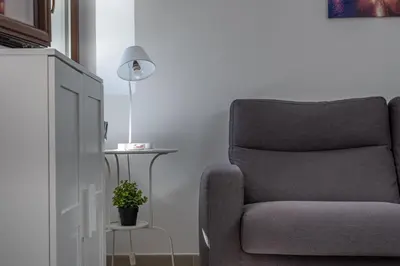 a chair in a living room with a lamp and a plant at Lumar Sicilia - Quaroni in Palermo