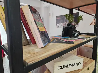 a book shelf with books and a camera on it at Porta D ossuna comfort apartments in Palermo