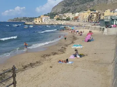 a group of people on a beach with an umbrella at Nela Appartament in Bagheria