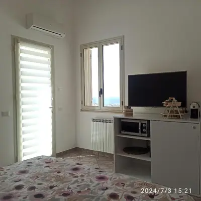 a white room with a tv and a tv stand with a television at Mediterraneo Rooms in Castellammare del Golfo