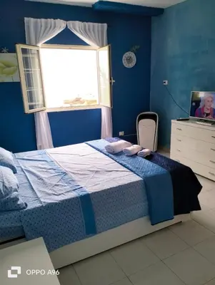 a blue bedroom with a bed and a window at LA TERRAZZA SUL MARE camera fronte mare&vicino aereoporto SICILIAN VINTAGE STYLE SEASIDE ROOM in Cinisi