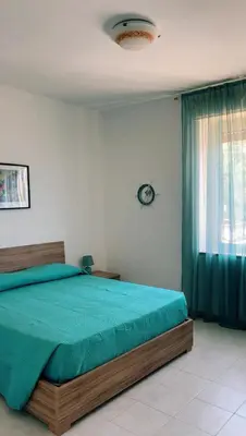 a bedroom with a bed with a green comforter and a window at Casa Iohana in San Vito lo Capo