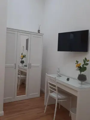 a white room with a desk and a tv on a wall at Aurora Center City - Rooms in Palermo