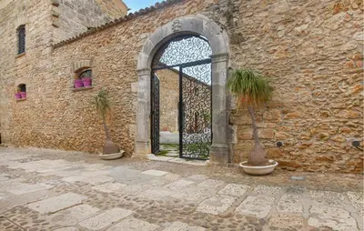 a stone building with a gate with two potted plants at 3 Bedroom Amazing Home In Partinico in Partinico