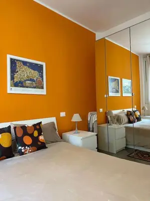 a bedroom with orange walls and a bed and a mirror at coppola home in Palermo