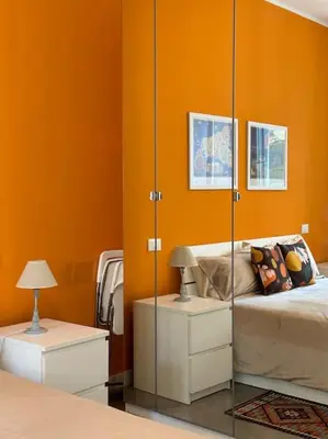 a bedroom with orange walls and a bed with a mirror at coppola home in Palermo